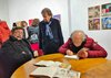 Trombini firma i suoi libri. Davanti a lui i bozzetti originali