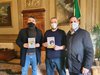 Consegna del romanzo al sindaco Alan Fabbri dall'autore Enrico Losso (a destra) insieme con il consigliere Francesco Carità (a sinistra del sindaco)